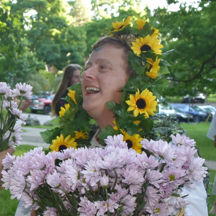 the Goddess smiles while wearing and carrying flowers